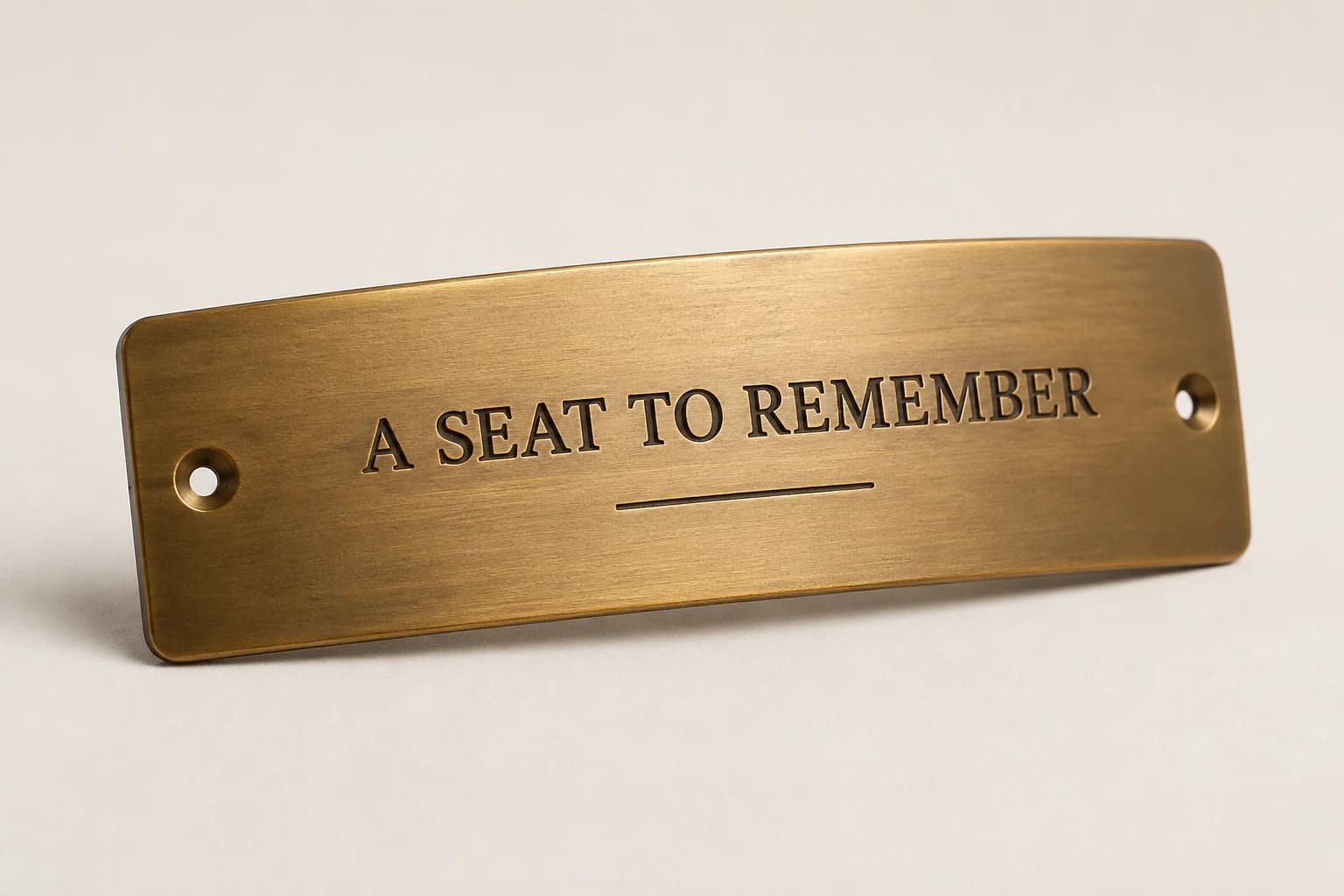 Curved brass bar-rail dedication plaque with a remembrance inscription.