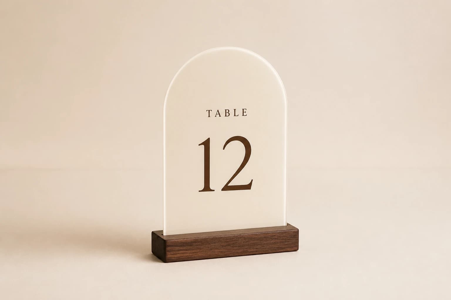 Ivory acrylic table number with an arched face and walnut slot base.